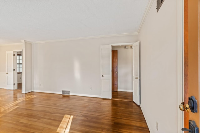 empty room with crown molding, hardwood / wood-style floors, and a textured ceiling