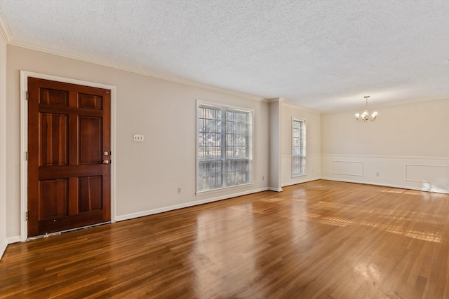 interior space with hardwood / wood-style flooring, ornamental molding, a textured ceiling, and a notable chandelier