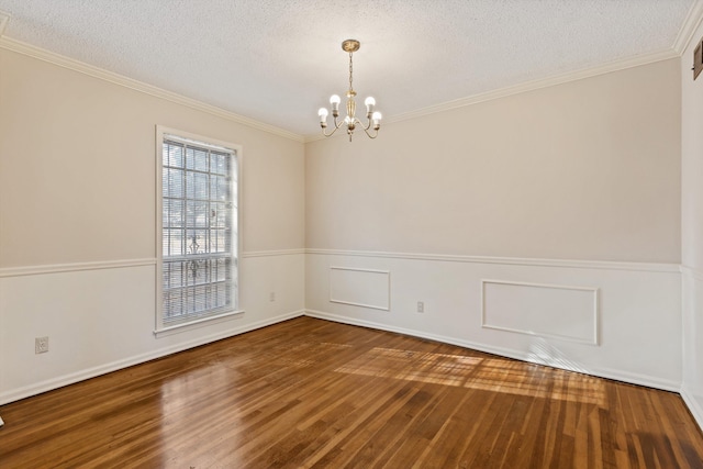 spare room with a textured ceiling, hardwood / wood-style flooring, an inviting chandelier, and crown molding