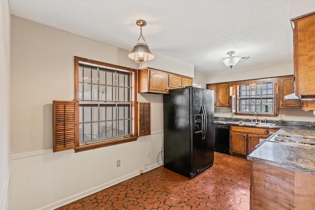 kitchen with a textured ceiling, sink, exhaust hood, black appliances, and hanging light fixtures