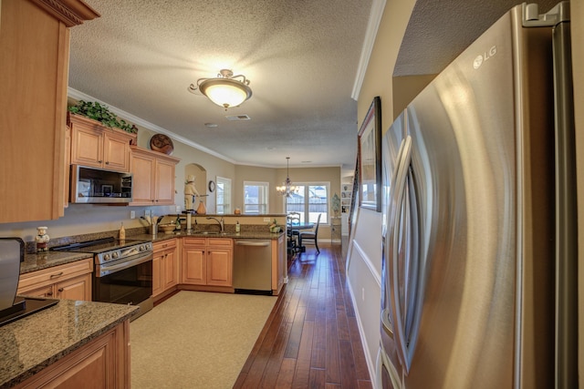 kitchen with an inviting chandelier, hanging light fixtures, light hardwood / wood-style floors, kitchen peninsula, and stainless steel appliances