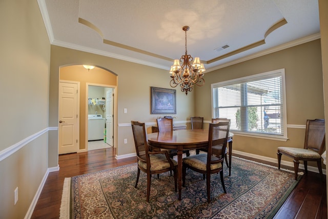 dining room featuring a tray ceiling, washer / clothes dryer, crown molding, and dark hardwood / wood-style flooring