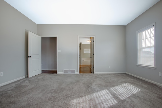 unfurnished bedroom with light carpet and connected bathroom