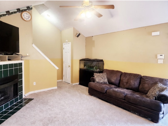 living room with carpet, vaulted ceiling, ceiling fan, and a tiled fireplace