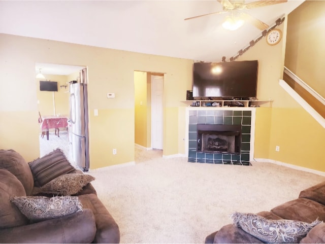 living room with carpet flooring, ceiling fan, and a tiled fireplace