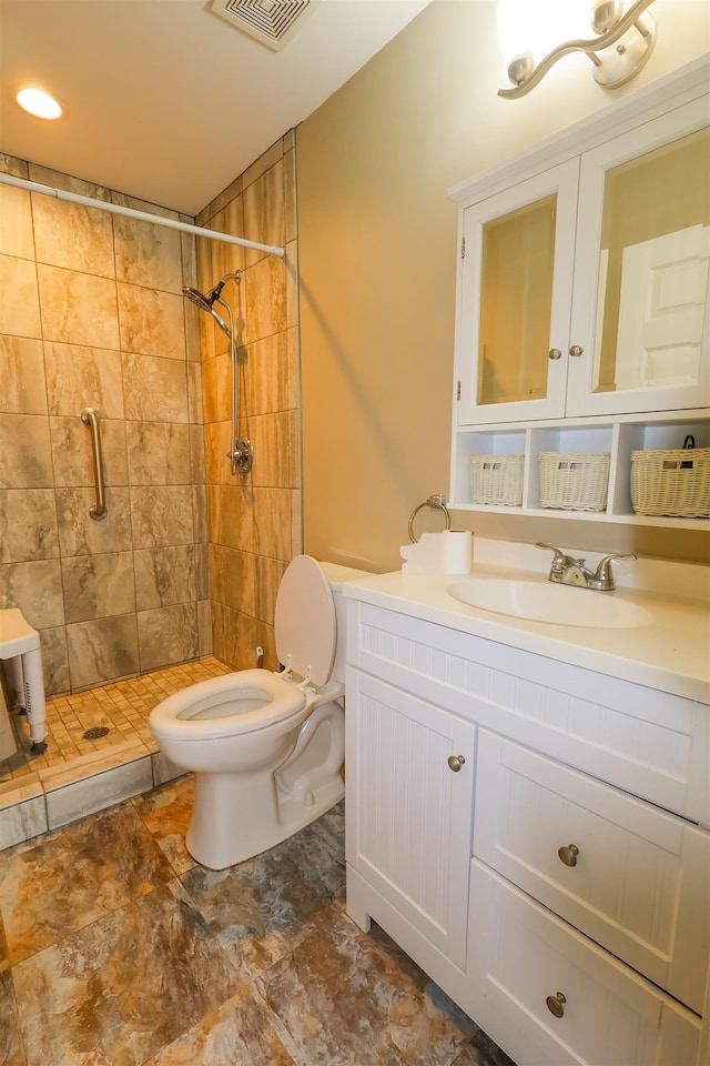 bathroom featuring a tile shower, vanity, and toilet