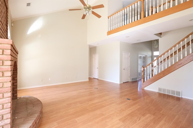 living room featuring ceiling fan, a towering ceiling, ornamental molding, and light hardwood / wood-style floors