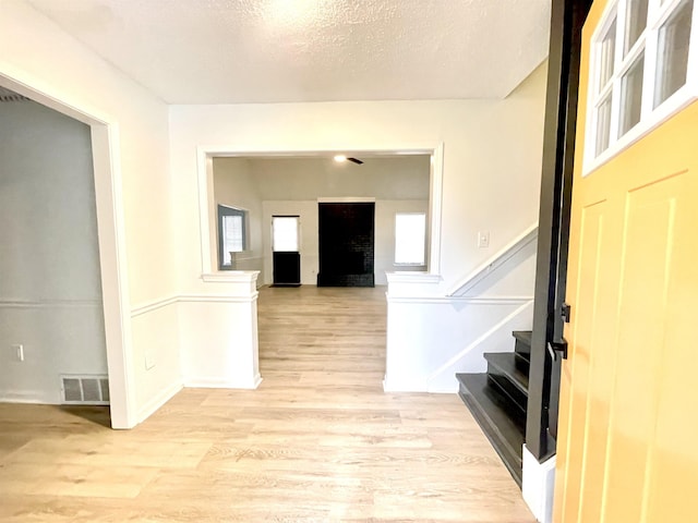 foyer with a fireplace, light hardwood / wood-style flooring, and a textured ceiling