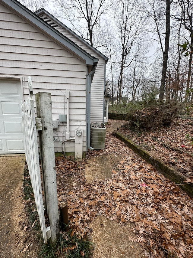 view of property exterior featuring cooling unit and a garage