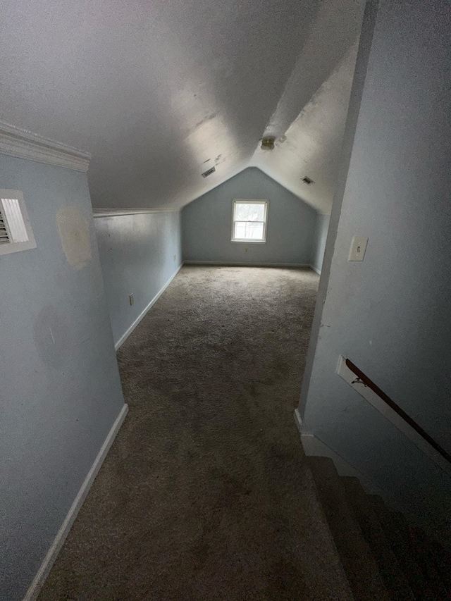 additional living space featuring a textured ceiling, dark carpet, and lofted ceiling