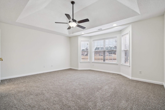 carpeted empty room with ceiling fan, a textured ceiling, and a tray ceiling