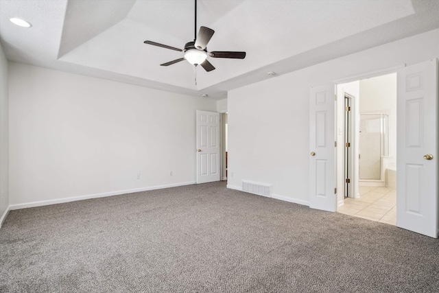 unfurnished bedroom with light carpet, connected bathroom, a raised ceiling, and ceiling fan