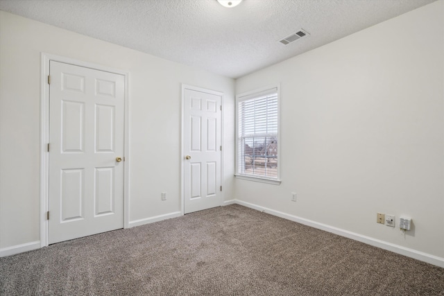 unfurnished bedroom with a textured ceiling and carpet floors