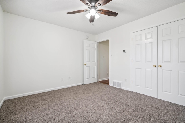 unfurnished bedroom with dark colored carpet, a closet, and ceiling fan