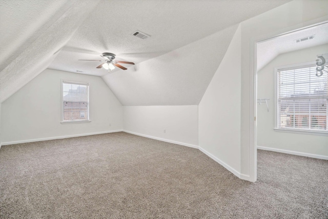 bonus room featuring a wealth of natural light, carpet floors, a textured ceiling, and ceiling fan