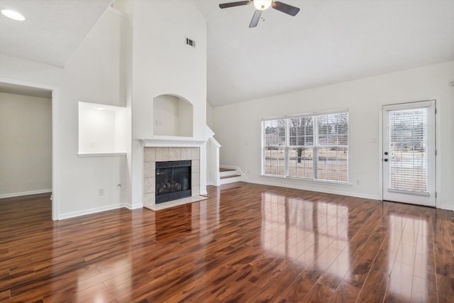 unfurnished living room with a tile fireplace, ceiling fan, and dark wood-type flooring