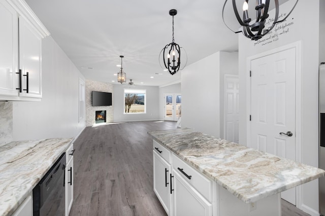 kitchen with a large fireplace, dishwasher, white cabinets, hardwood / wood-style floors, and a kitchen island