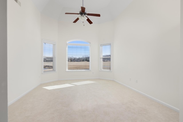 carpeted empty room with ceiling fan and high vaulted ceiling