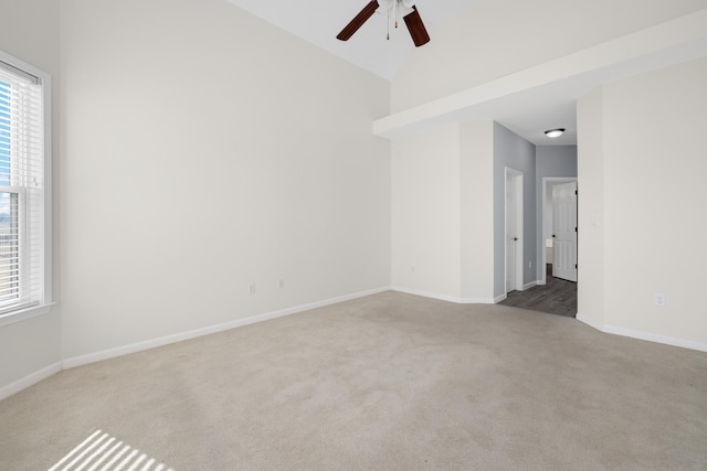 spare room featuring light carpet, vaulted ceiling, and ceiling fan