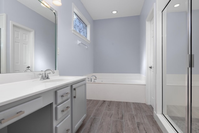 bathroom with hardwood / wood-style floors, vanity, and plus walk in shower