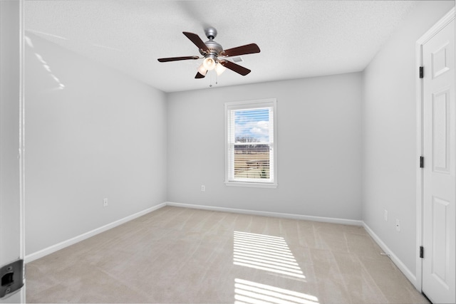 empty room featuring ceiling fan, light colored carpet, and a textured ceiling