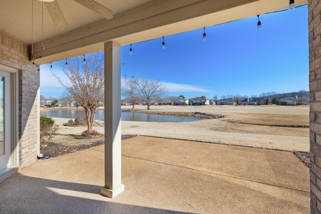 view of patio with a water view and ceiling fan