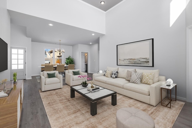 living room featuring a chandelier, a high ceiling, light hardwood / wood-style floors, and crown molding