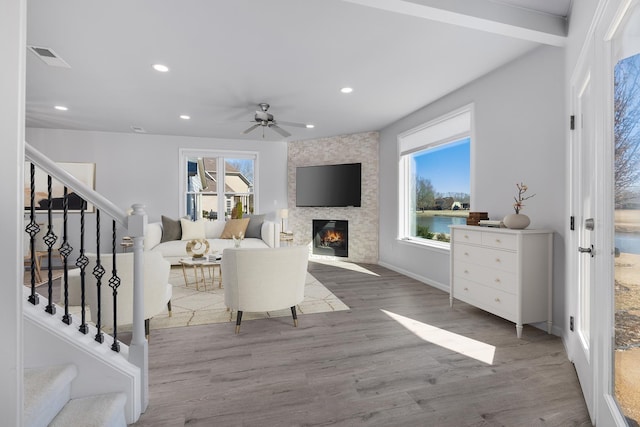 living room featuring ceiling fan, hardwood / wood-style floors, beamed ceiling, and a healthy amount of sunlight