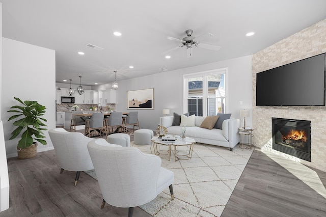 living room with ceiling fan, a fireplace, and light wood-type flooring