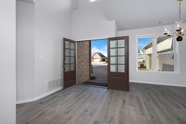 entryway with a healthy amount of sunlight, french doors, wood-type flooring, and an inviting chandelier