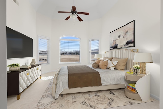 carpeted bedroom with ceiling fan and a towering ceiling