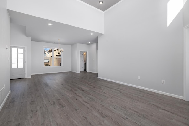 unfurnished living room with a chandelier, wood-type flooring, crown molding, and a high ceiling