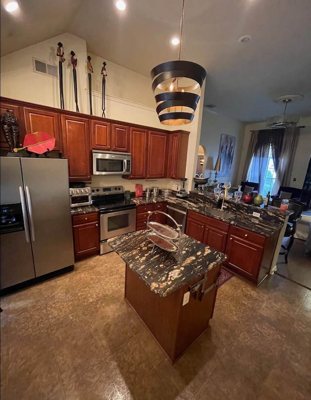 kitchen with dark stone counters, sink, vaulted ceiling, appliances with stainless steel finishes, and kitchen peninsula