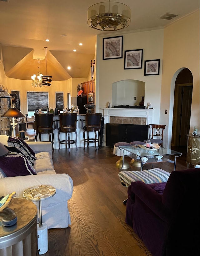 living room featuring dark hardwood / wood-style flooring, a notable chandelier, lofted ceiling, and a tiled fireplace