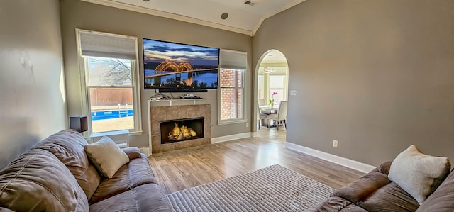 living room with light hardwood / wood-style flooring, ornamental molding, a fireplace, and vaulted ceiling