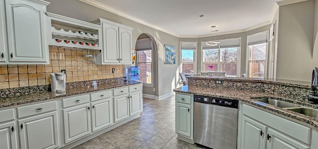 kitchen featuring dishwasher, light tile patterned floors, crown molding, dark stone counters, and white cabinets