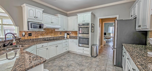 kitchen with appliances with stainless steel finishes, white cabinetry, and sink