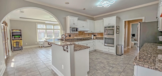 kitchen featuring dark stone countertops, light tile patterned floors, appliances with stainless steel finishes, tasteful backsplash, and white cabinetry