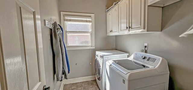 clothes washing area with cabinets, light tile patterned floors, and washing machine and dryer