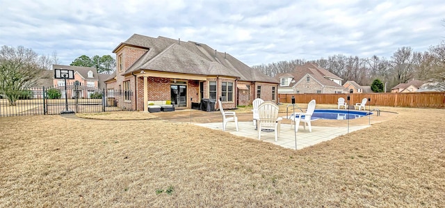 back of house featuring a yard, a fenced in pool, and a patio area