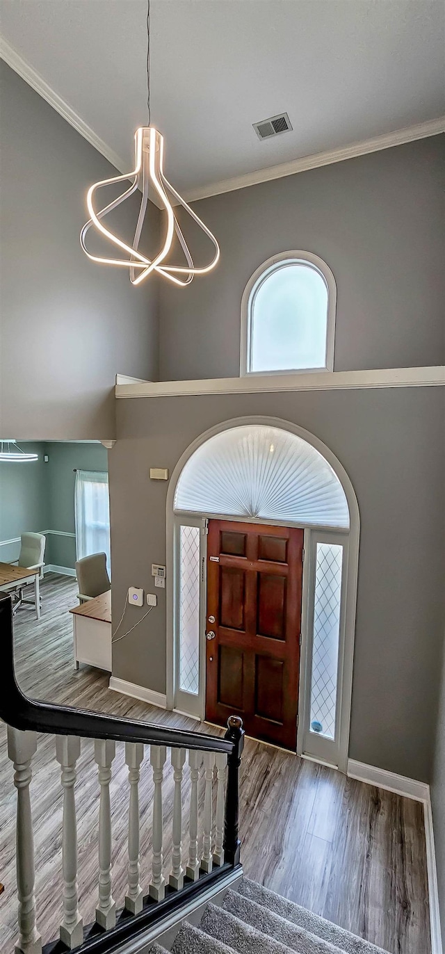 entryway featuring ornamental molding, a healthy amount of sunlight, a notable chandelier, and wood-type flooring