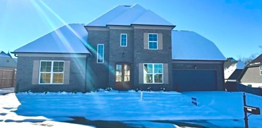 snow covered rear of property with a garage