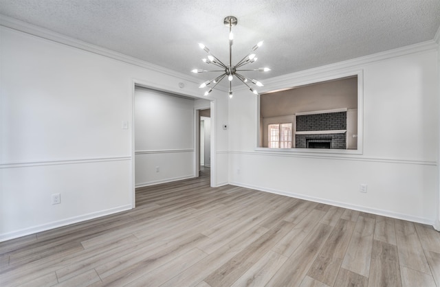 empty room with an inviting chandelier, a textured ceiling, and a brick fireplace