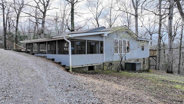 view of side of home with central AC and a sunroom