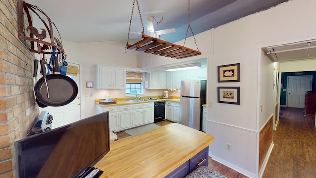 kitchen with white cabinetry, black dishwasher, stainless steel fridge, vaulted ceiling, and hardwood / wood-style flooring