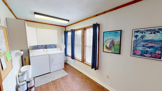 washroom featuring washer and clothes dryer, cabinets, dark wood-type flooring, crown molding, and a textured ceiling