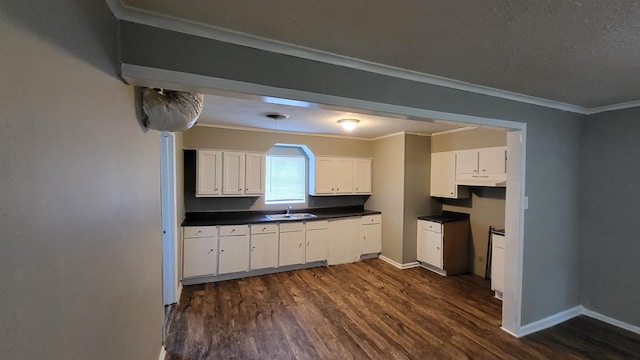 kitchen featuring dark hardwood / wood-style floors, white cabinetry, ornamental molding, and sink