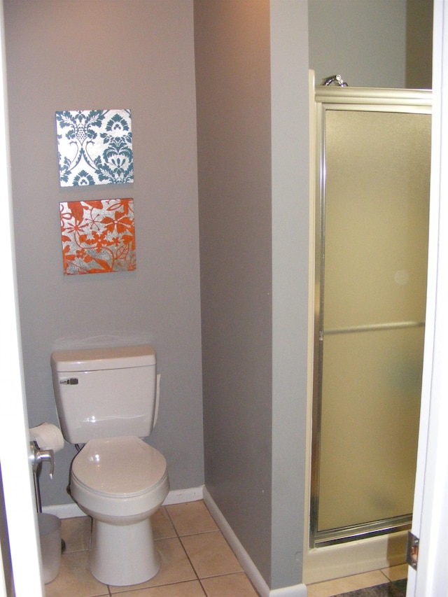 bathroom featuring tile patterned flooring, a shower with shower door, and toilet