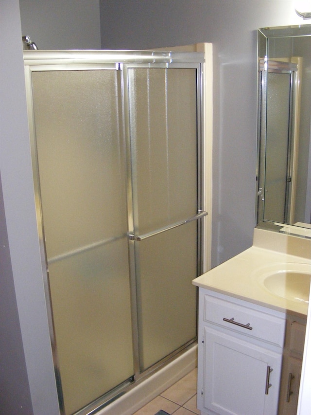 bathroom with an enclosed shower, vanity, and tile patterned floors