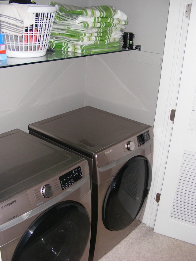 clothes washing area with light colored carpet and washing machine and clothes dryer